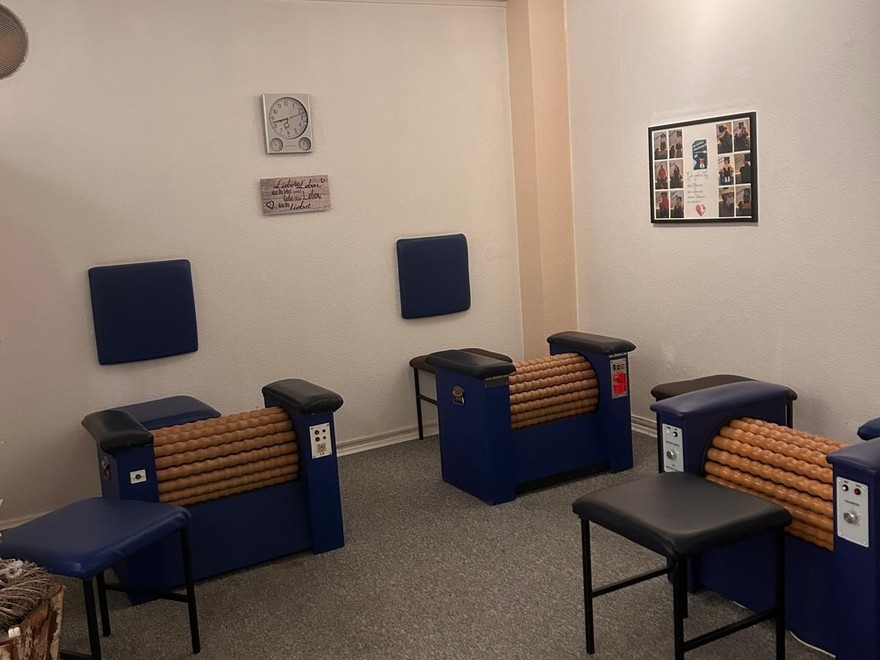 Mehrere Rollenpritschen nebeneinander im Studio: blaue Liegen mit hölzernen Rollen in der Mitte